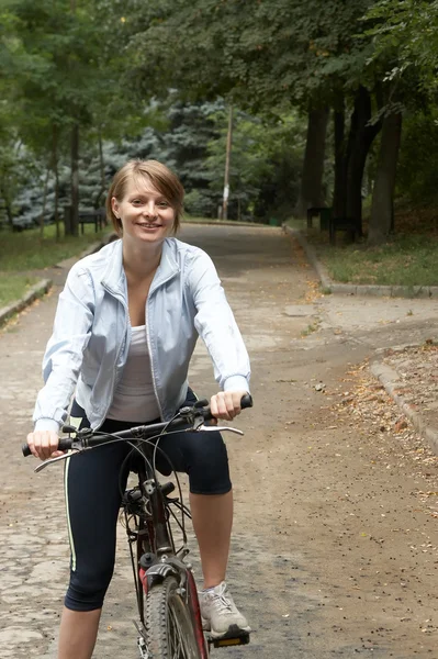 Młoda kobieta jazdy uśmiechający się rower — Zdjęcie stockowe