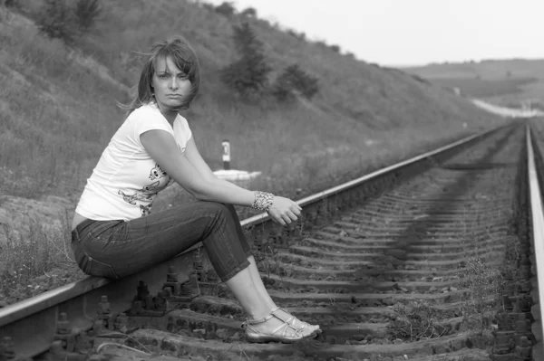 Mladá žena sedící na železnici — Stock fotografie