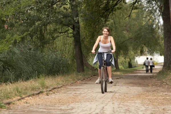 젊은 여성 승마 웃는 자전거 스톡 이미지