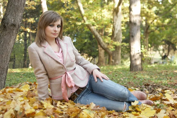 Młoda kobieta siedzi w parku — Zdjęcie stockowe