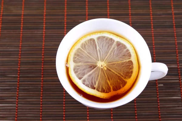 stock image Cup of tea with a lemon on bamboo napkin