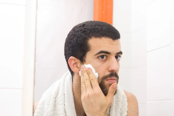 Mann rasiert sich und schaut in den Spiegel — Stockfoto