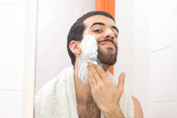 Мужчина бреется и смотрит в зеркало — стоковое фото