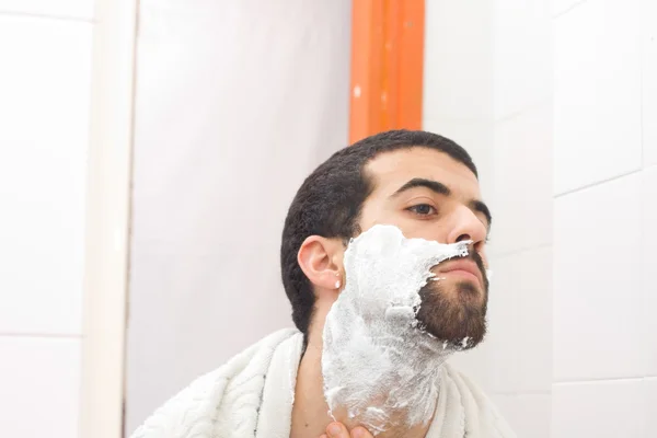 Мужчина бреется и смотрит в зеркало — стоковое фото