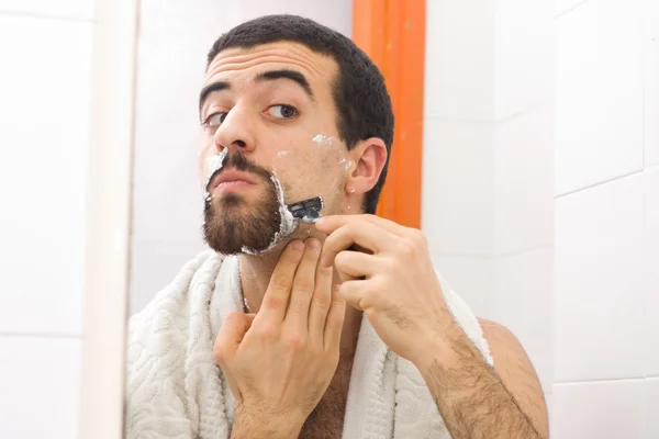 Man shaving and looking to the mirror — Stock Photo, Image