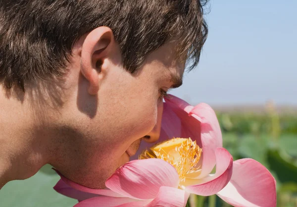 Joven oliendo un loto rosa —  Fotos de Stock