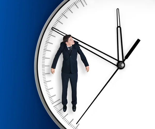 Businessman hangs on an arrow of clock — Stock Photo, Image
