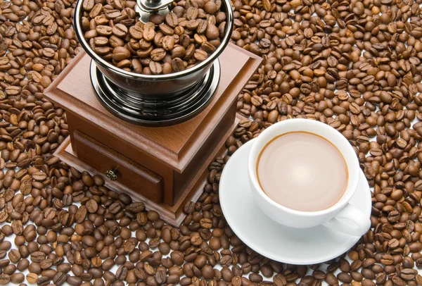 Старая кофемолка и чашка кофе — стоковое фото