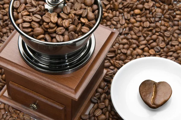 Старая кофемолка и сердце на блюдце — стоковое фото