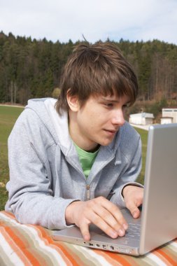 Teenager outside with laptop clipart