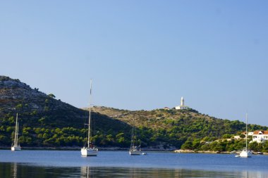 White sailing yacht on an anchor in harbor clipart