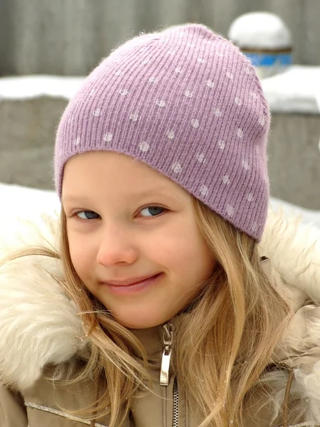 Glad liten tjej i en lila hatt. Stockbild