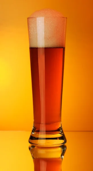 Um copo de cerveja em um fundo amarelo — Fotografia de Stock