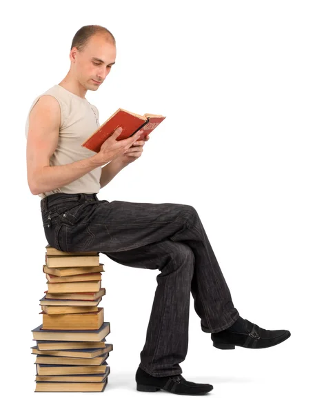 Mann sitzt auf Bücherhaufen — Stockfoto