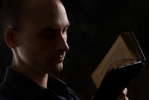 Hombre leyendo un libro en la oscuridad — Foto de Stock