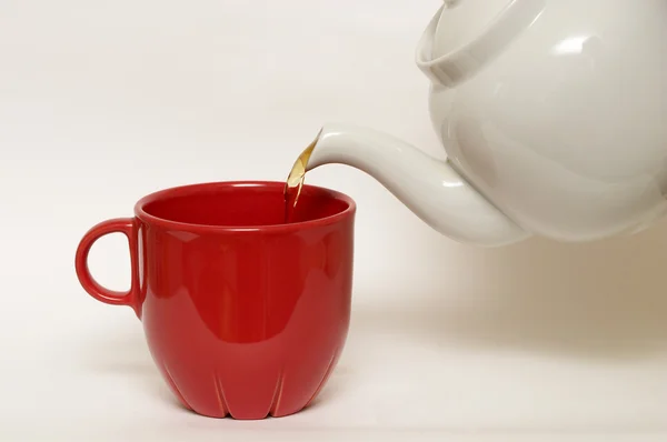 Fehér mázas fajansz teáskanna és a piros pohár — Stock Fotó