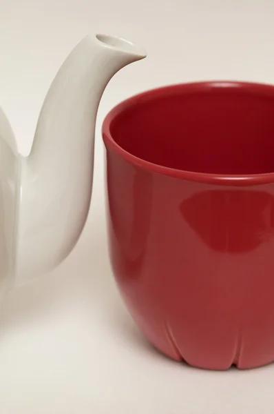 Bílé glazované fajáns čajové konvice a červené cup — Stock fotografie