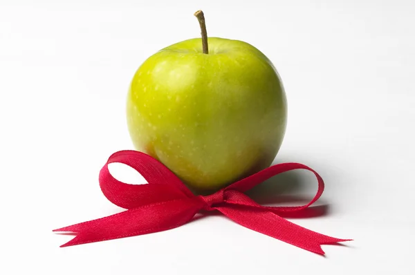 Green apple and red ribbon bow — Stock Photo, Image