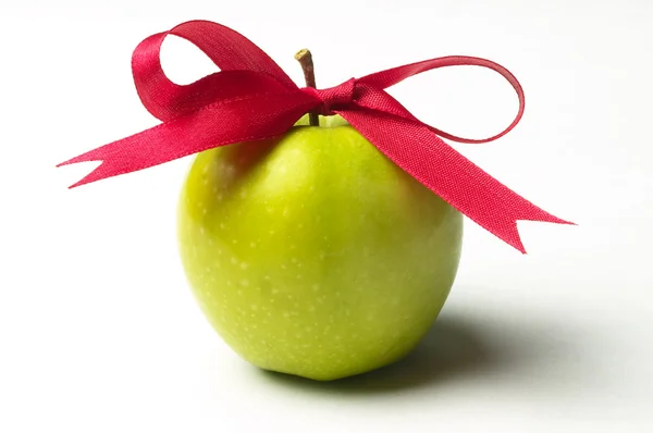 Green apple and red ribbon bow — Stock Photo, Image