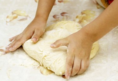 Hands of the child knead the dough for a clipart