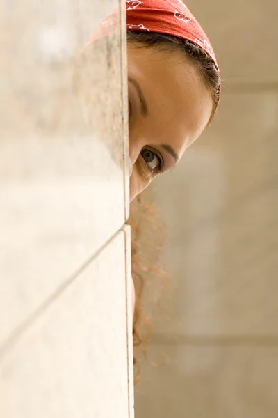 Woman looking behind a wall — Stock Photo, Image