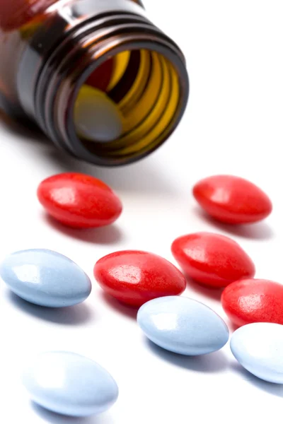 Garrafa com comprimidos vermelhos e azuis — Fotografia de Stock