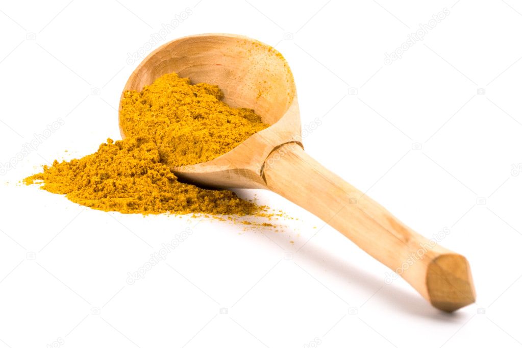 Yellow turmeric on wooden spoon
