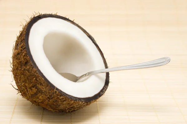 Half coconut with a spoon on a rug. — Stock Photo, Image