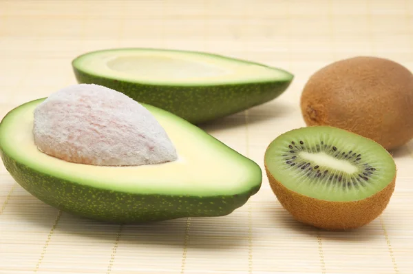 Two halves of avocado, kiwi on a rug. — Stock Photo, Image