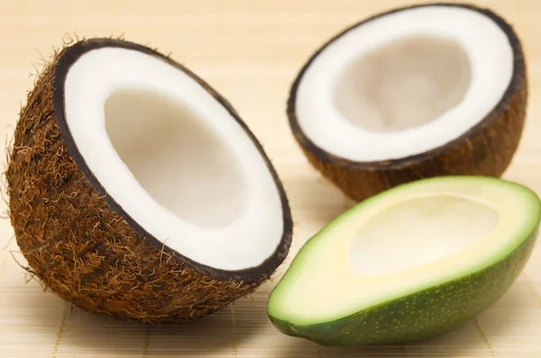 Two halves of coconut, avocado on a rug. — Stock Photo, Image