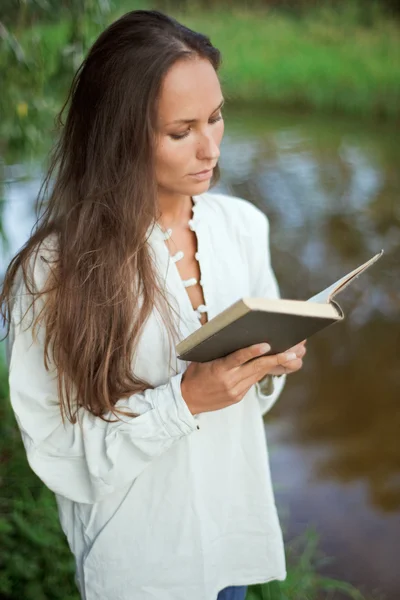 Reading young woman near the river — Stock Photo, Image