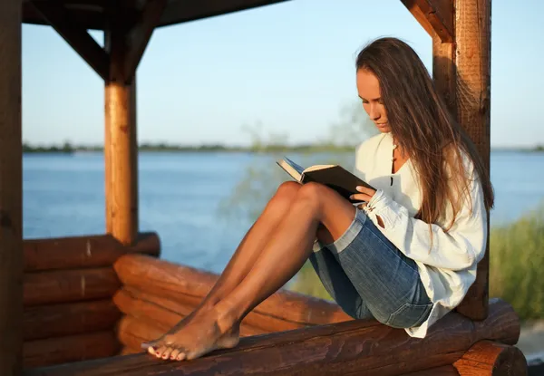 Young woman reading book in summerhouse — Stock Photo, Image
