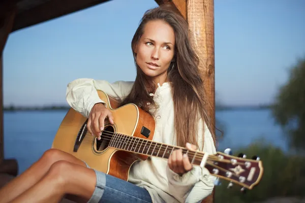 Νεαρή γυναίκα που παίζει κιθάρα σε summerhous — Φωτογραφία Αρχείου