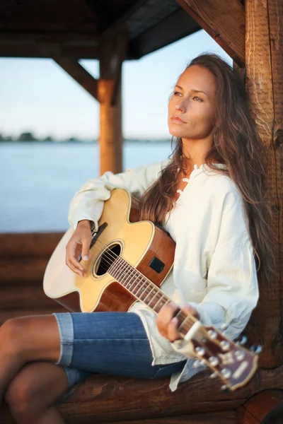 Νεαρή γυναίκα που παίζει κιθάρα σε summerhous — Φωτογραφία Αρχείου
