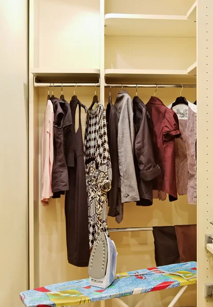 Garderobe met kleding en strijkplank — Stockfoto