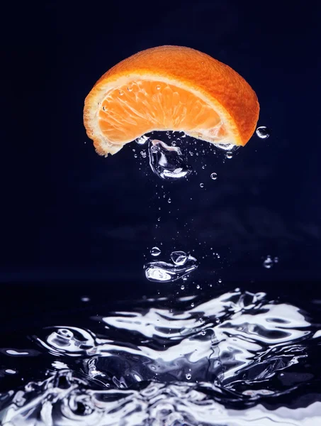Naranja (mandarina) cayendo en agua azul — Foto de Stock