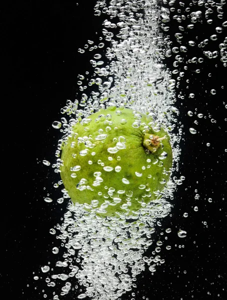 Lime (citron) faller i vattnet på svart — Stockfoto