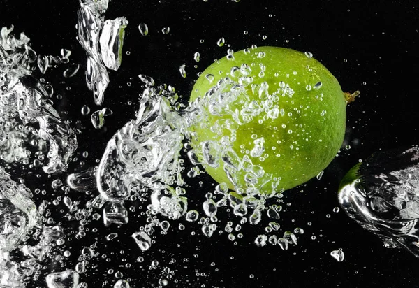 Limau (lemon) jatuh dalam air di atas hitam — Stok Foto