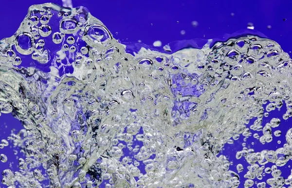 Брызги воды с пузырьками воздуха на голубом — стоковое фото