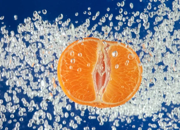 Naranja (mandarina) flotando en agua azul — Foto de Stock