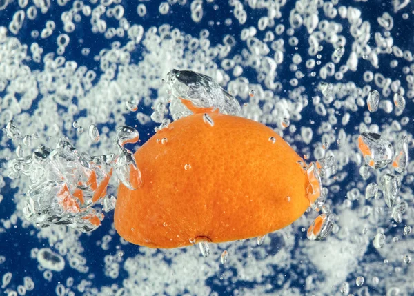 Naranja (mandarina) flotando en agua azul — Foto de Stock