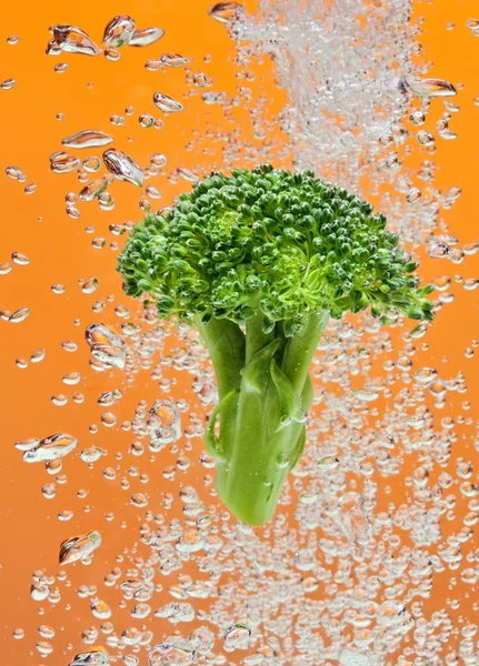 Green broccoli falling in water — Stock Photo, Image