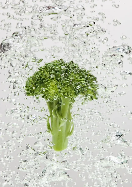Green broccoli falling in water — Stock Photo, Image