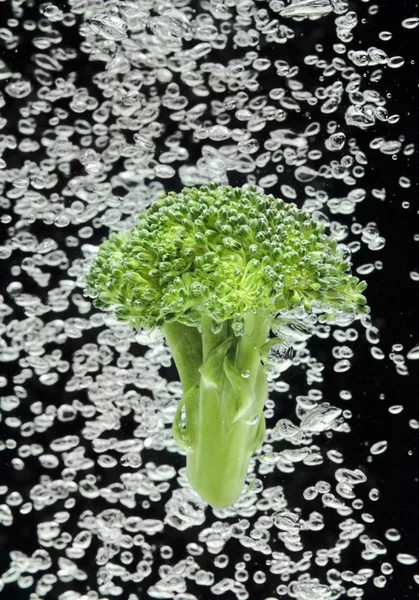 Groene broccoli vallen in water — Stockfoto