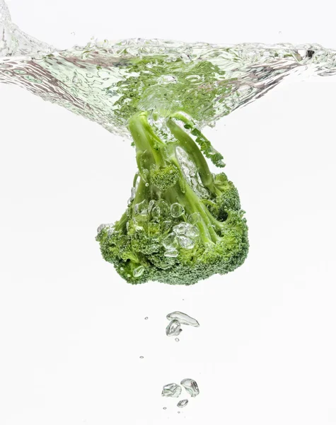 stock image Green broccoli falling in water