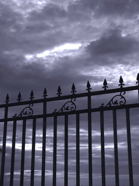Железный забор и мрачное небо — стоковое фото