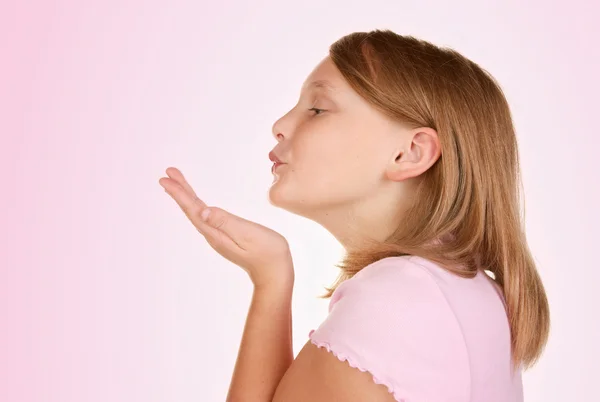 Junges Mädchen bläst einen Kuss auf rosa — Stockfoto
