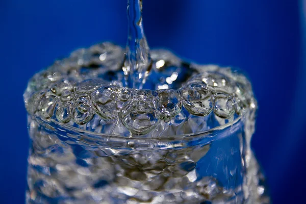 Droppar vatten hälls i ett glas — Stockfoto