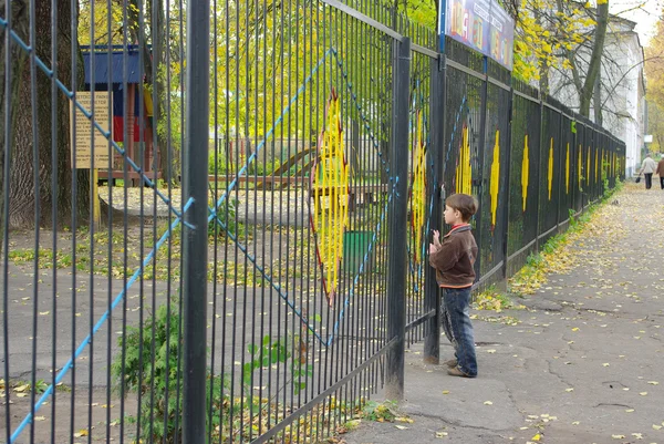 Ett barn står vid stängda portar — Stockfoto