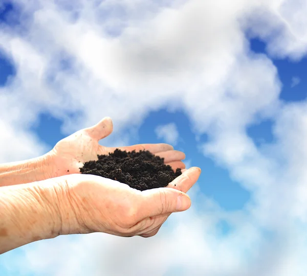 Soil in hands, sky wiht clouds — Stock Photo, Image